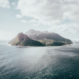 Île montagneuse vue de loin, encerclée par la mer